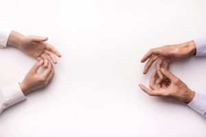 A husband and wife take off their engagement rings against a flat white background; collaborative divorce can have a significant impact on family wealth.